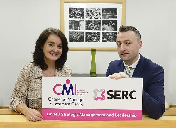 Jenny McConnell and Philip Martin, seated at table,  holding placard with CMI and SERC branding